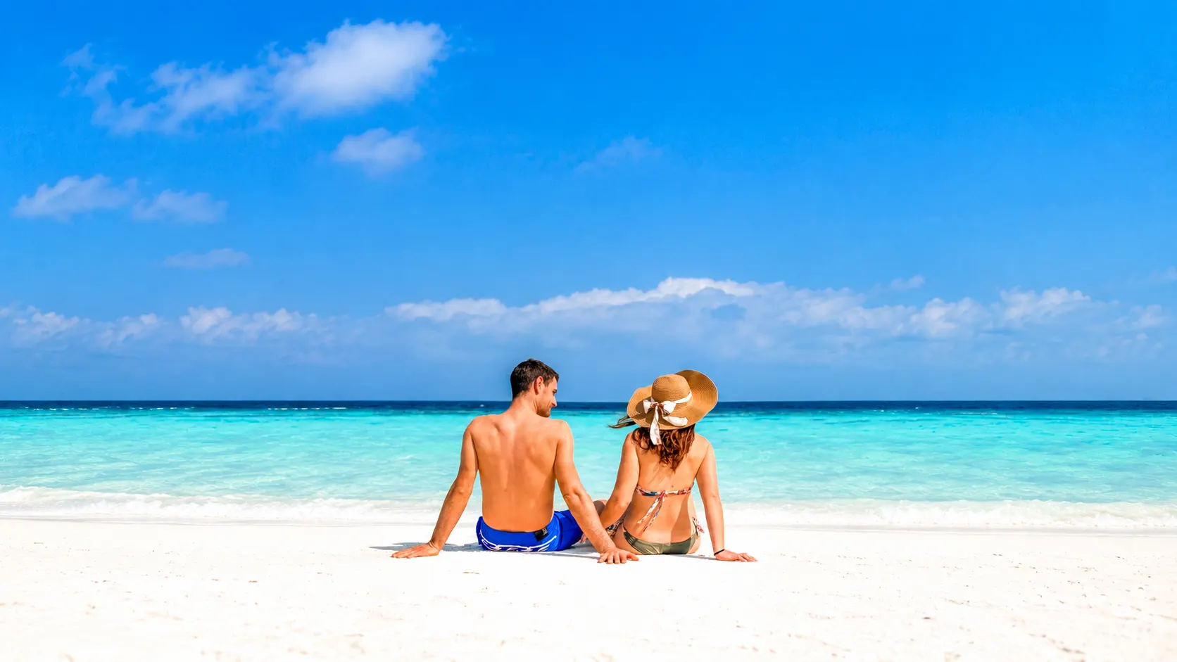Couple sitting on a white-sand beach