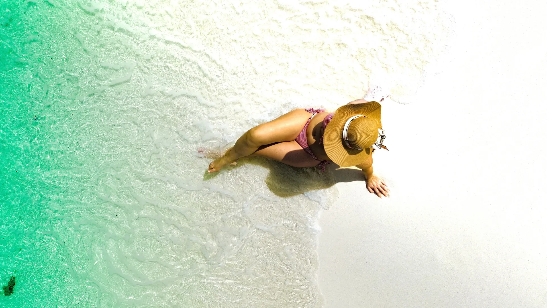 Guest relaxing where the lagoon meets white sand